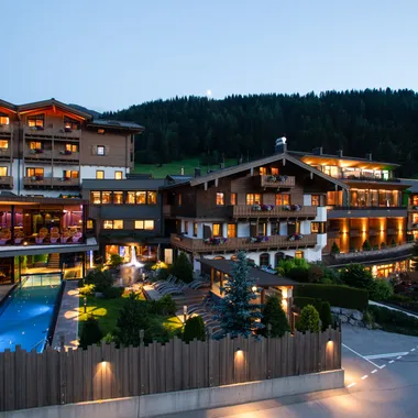 My Good Life Illuminated alpine hotel with outdoor pool and balconies at sunset